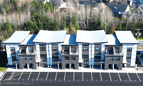 A parking lot in front of a building with grey and white exterior.