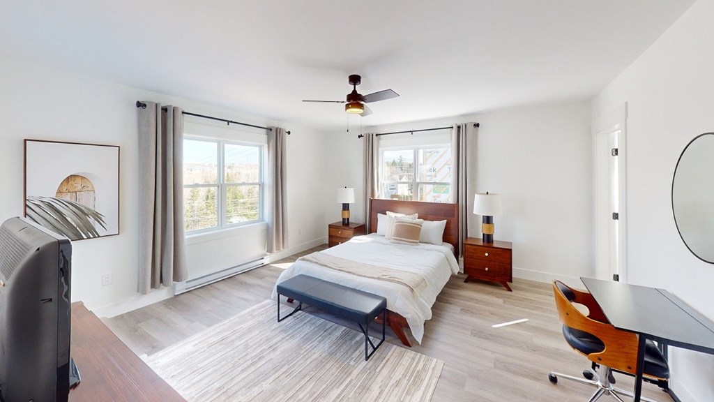 A bedroom with a bed, a chair, and a ceiling fan.