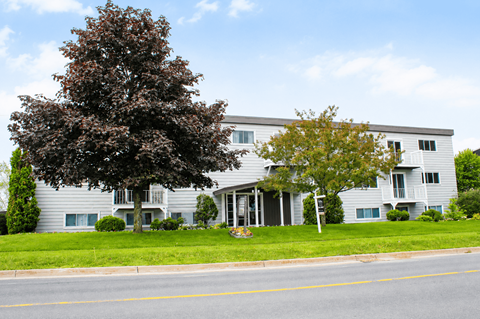 A grey building with a tree in front of it.