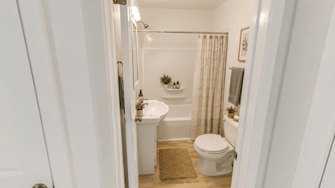 A white bathroom with a toilet, sink, and shower.