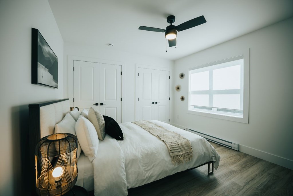 A bedroom with a bed, pillows, a lamp, and a ceiling fan.