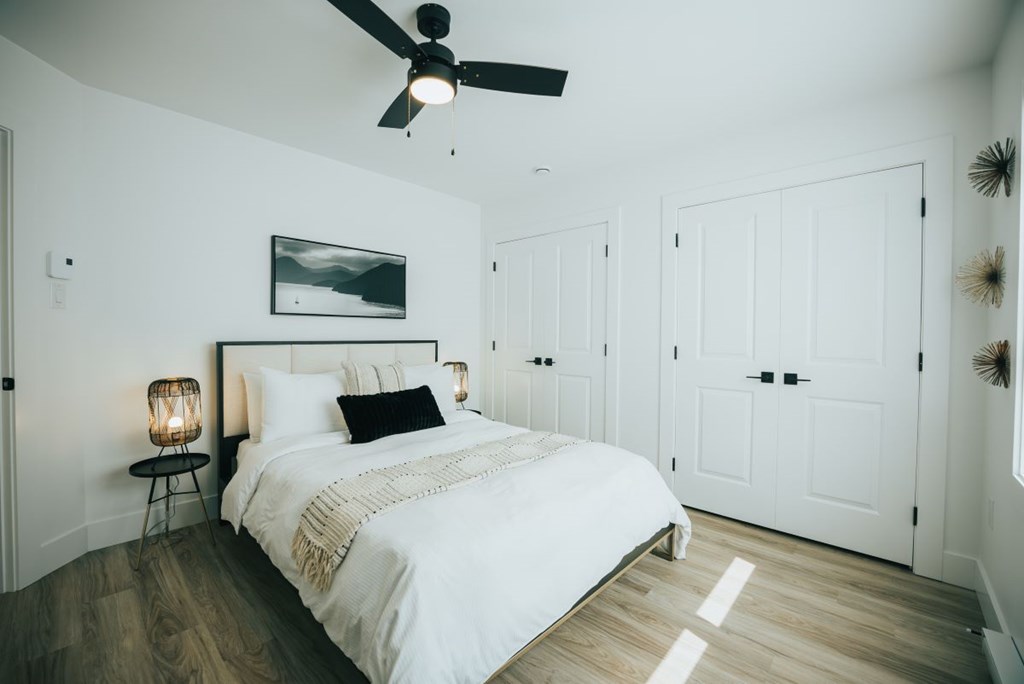 A bedroom with a large bed and a ceiling fan.