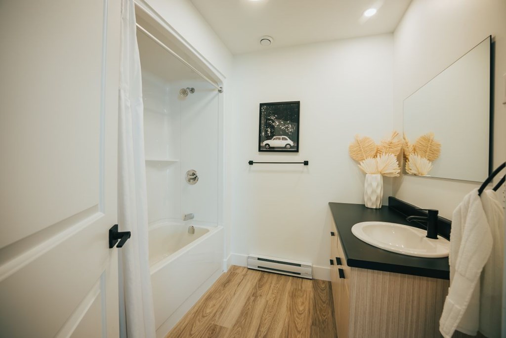 A bathroom with a sink, mirror, and a shower.