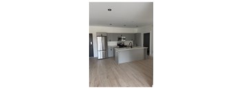 A modern kitchen with stainless steel appliances and wooden flooring.