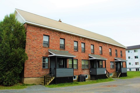 A red brick building with a white roof and a black door.