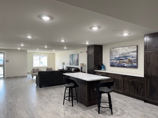 A modern kitchen with a bar area and a painting on the wall.