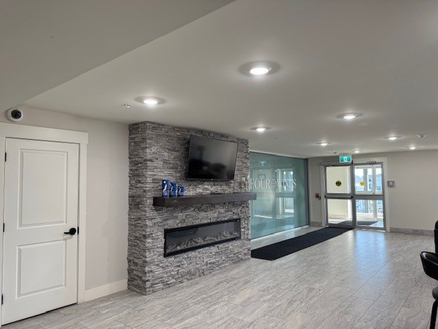 A living room with a stone fireplace and a flat screen TV mounted above it.
