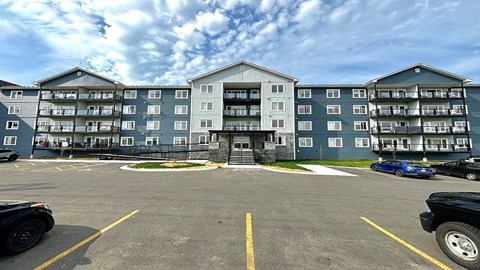 A parking lot in front of a large apartment building.