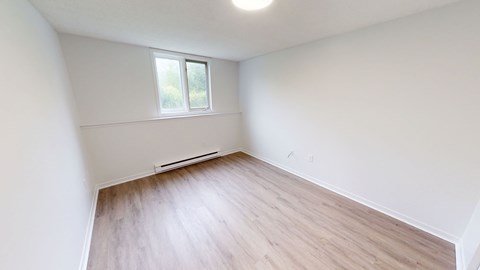 A room with a window and a wooden floor.