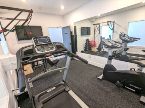 A treadmill and a stationary bike are in a well-lit room.