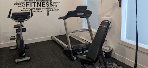 A gym room with a treadmill and a stationary bike.