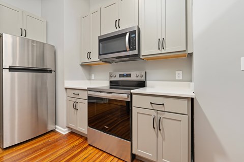 A kitchen with a stainless steel refrigerator, microwave, oven, and cabinets.