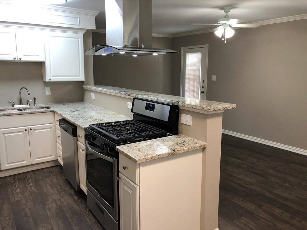 A kitchen with a black stove top oven and white cabinets.