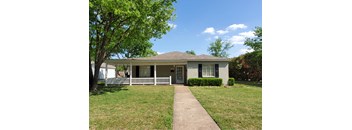 A house with a white fence and a tree in front.