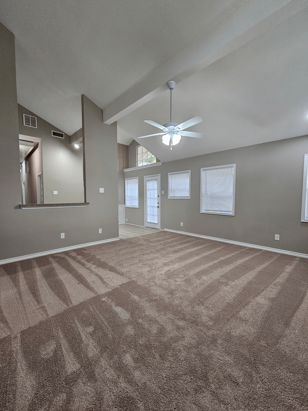 A room with a carpeted floor and a ceiling fan.