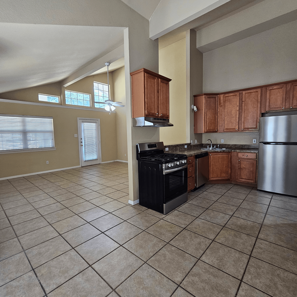 A kitchen with a black stove top oven and a silver refrigerator.