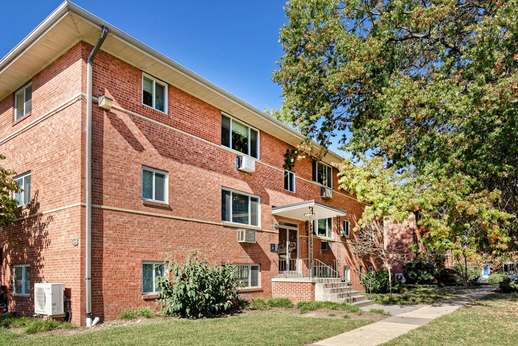 A red brick building with a tree in front.