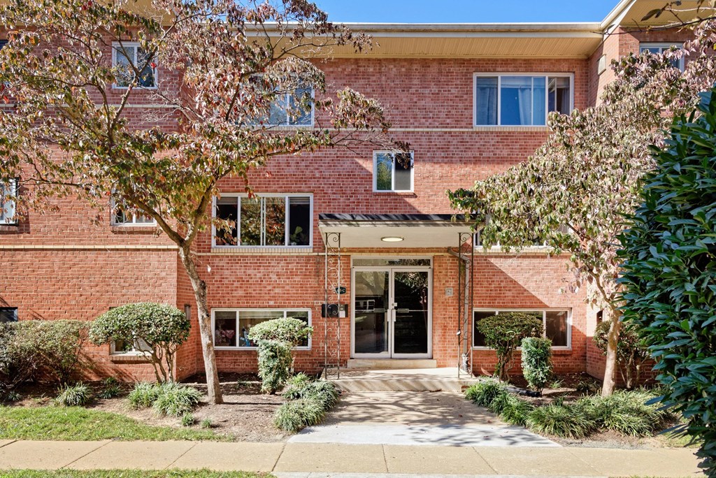 A red brick house with a tree in front.