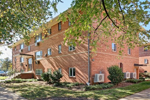 A red brick building with trees in front.