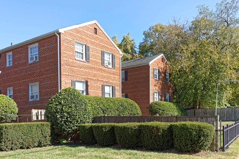 A red brick building with a black fence in front.