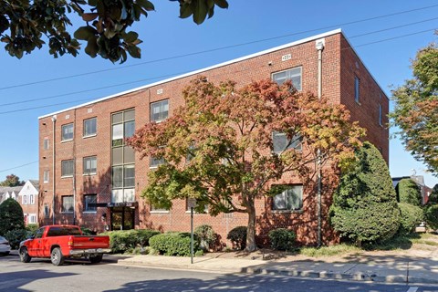 A red truck is parked on the street in front of a brick building.