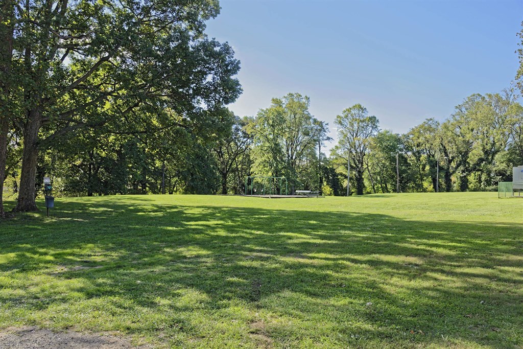 A park with a dirt path and a green grassy area.
