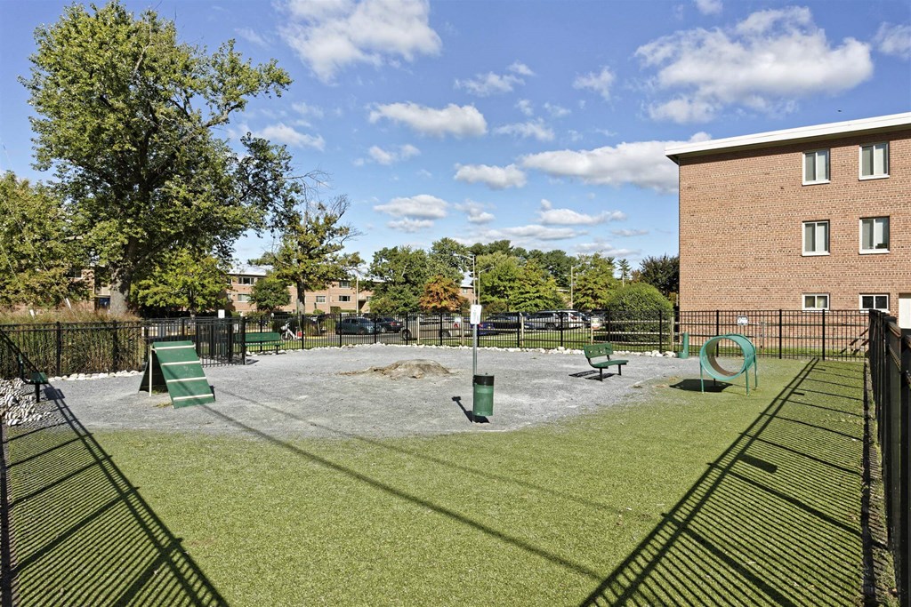 A dog park with a green slide and a brown building in the background.