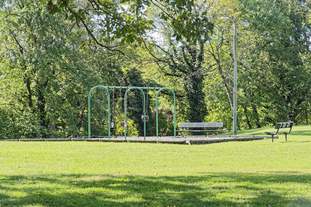 A park with a swing set and a bench.