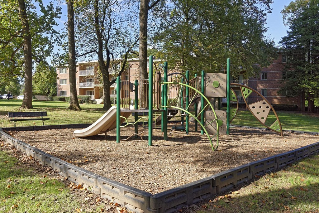A playground with a slide, swings, and a seesaw.