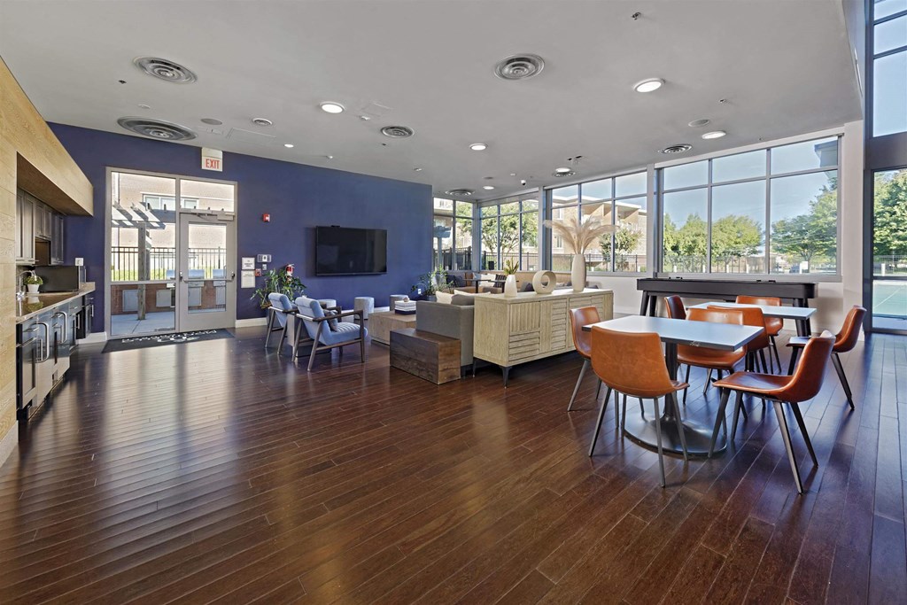 A spacious room with wooden floors and a large window overlooking a tree-filled area.