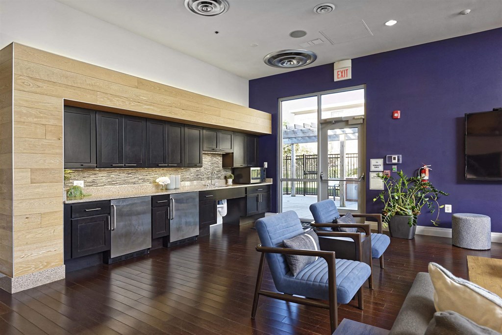 A modern kitchen with a wood grain island and blue chairs.