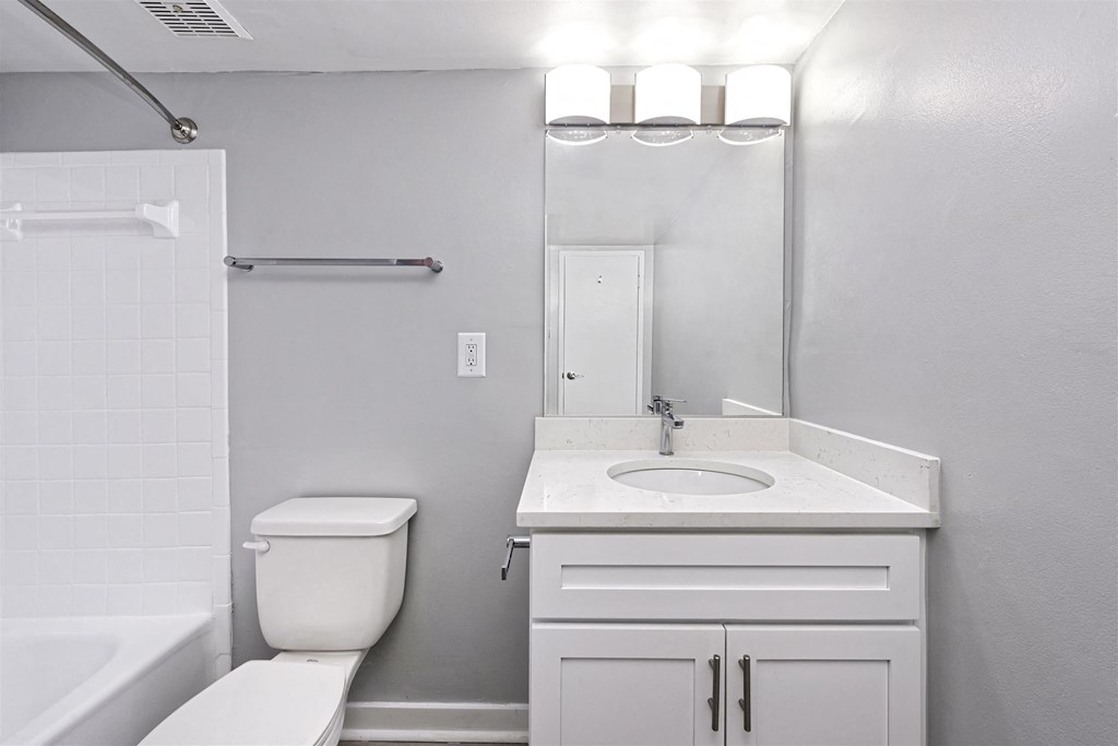 A white bathroom with a toilet, sink, and mirror.
