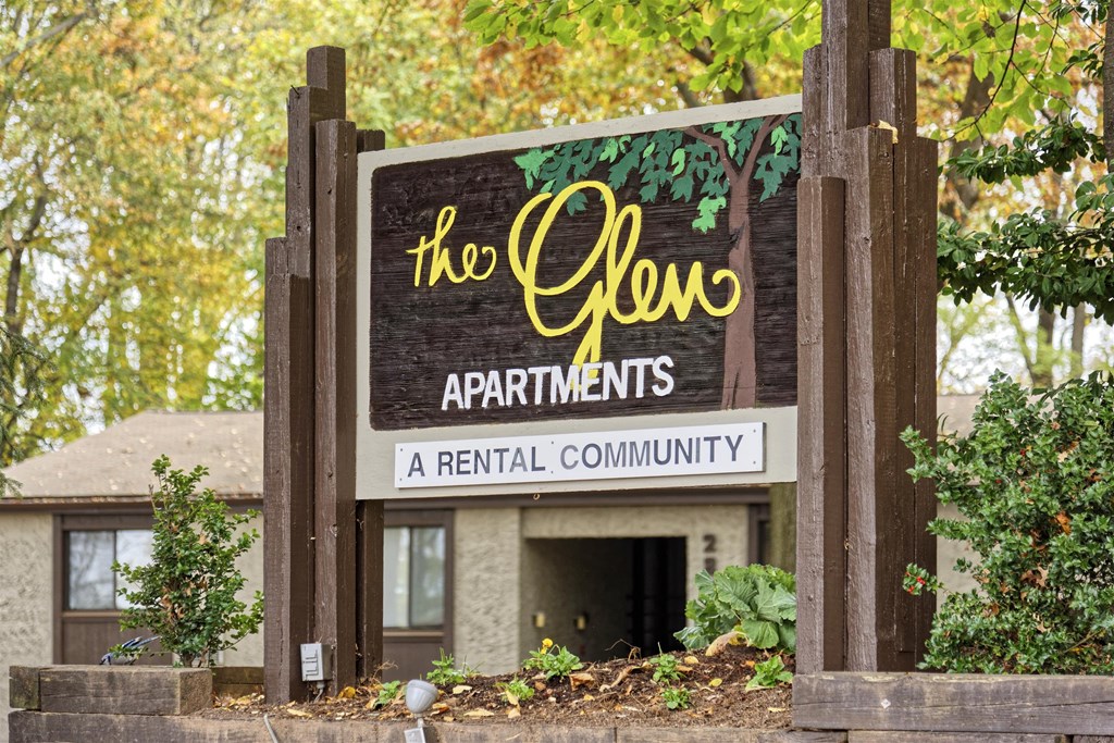 A sign for The Glen Apartments stands in front of a building.