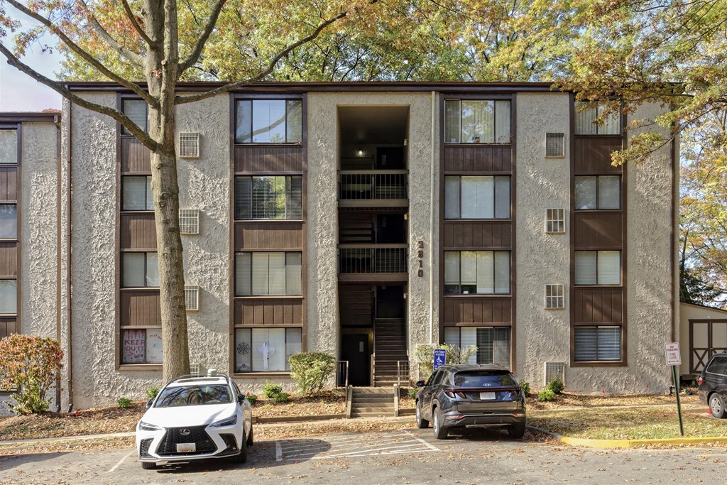A white Lexus SUV is parked in front of a brown apartment building.