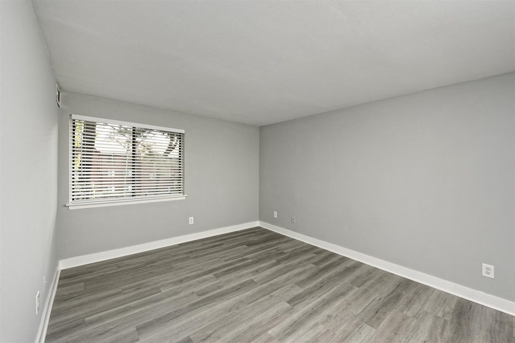 A room with a window and wooden flooring.