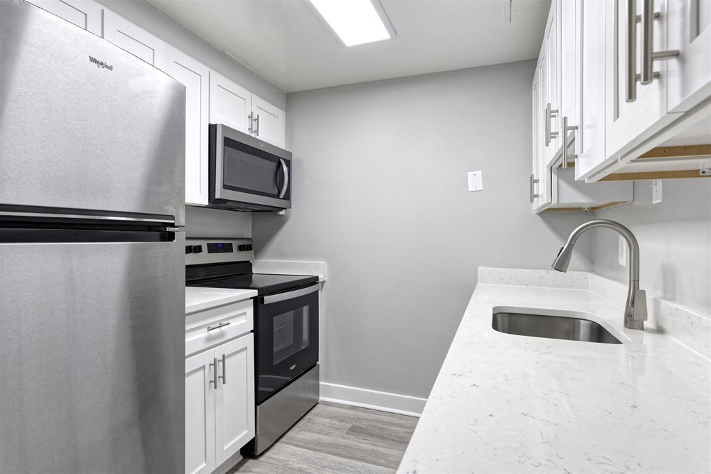 A kitchen with a stainless steel refrigerator, microwave, oven, and sink.