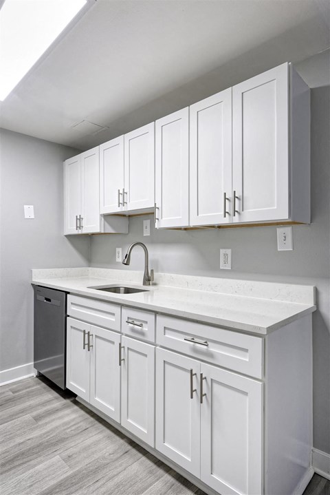 A kitchen with white cabinets and a white countertop.