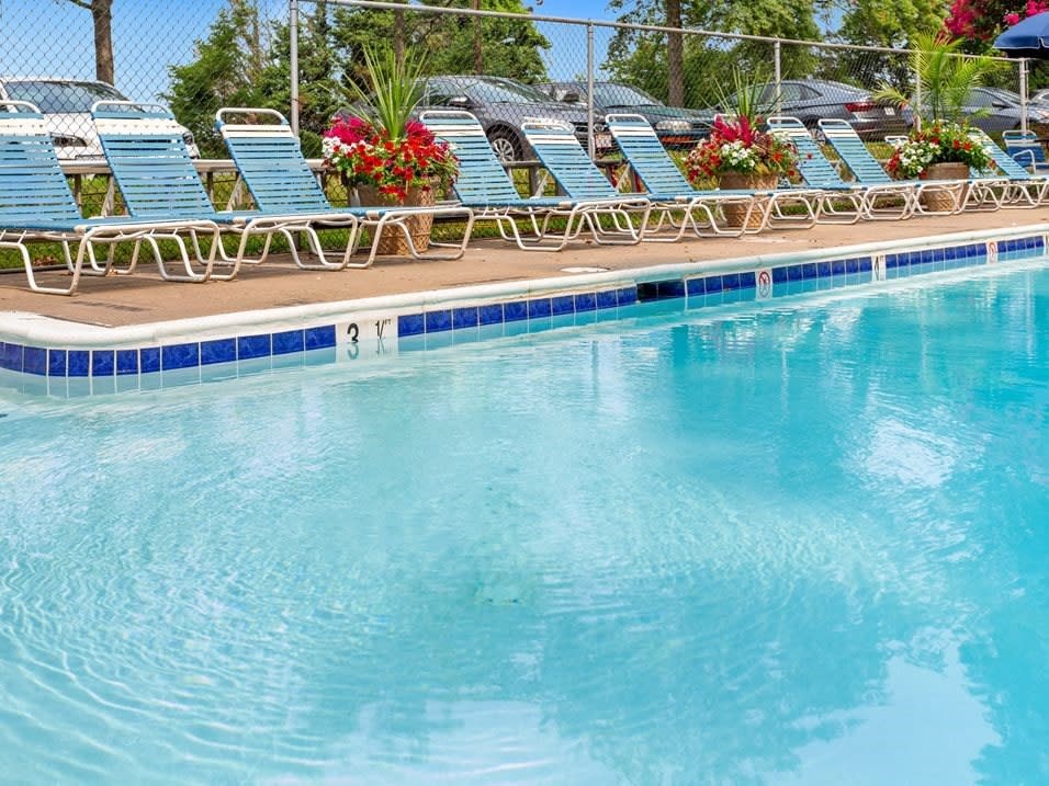A pool with blue water and chairs around it.