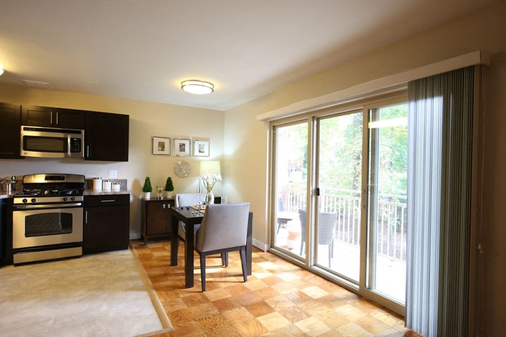 A kitchen with a table and chairs in front of a sliding glass door.