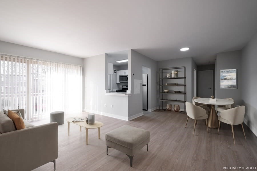 A modern living room with a grey couch, a coffee table, and a dining table set up.