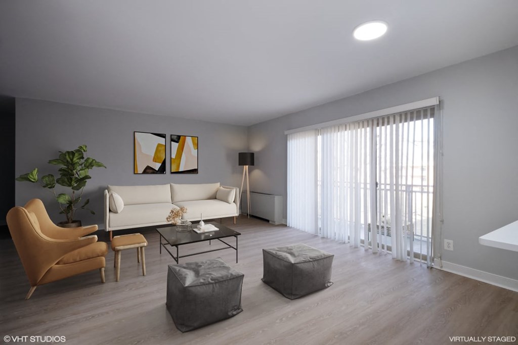 A living room with a white couch, a brown chair, a glass coffee table, and a grey ottoman.