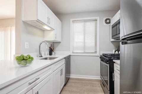 A kitchen with white cabinets and a stainless steel refrigerator.