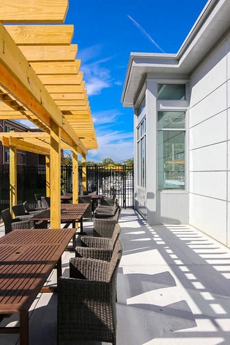 A sunny day at a modern outdoor seating area with wooden tables and chairs.