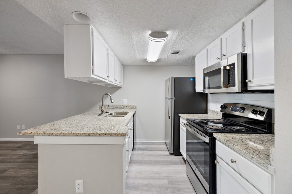 A kitchen with white cabinets and a granite countertop.