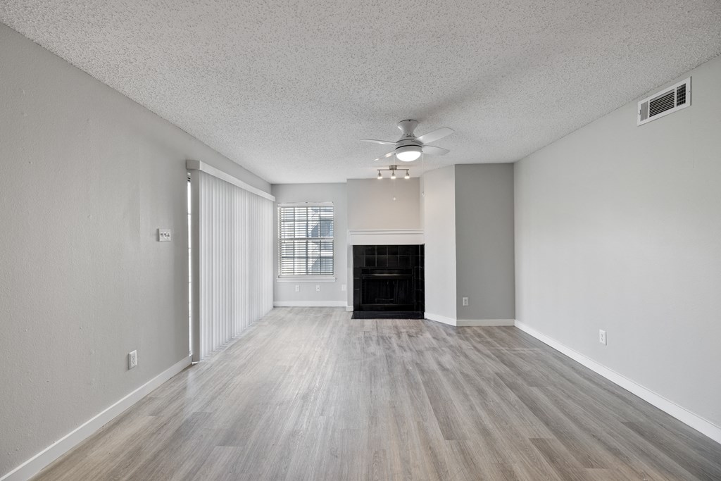 A spacious room with a fireplace and wood flooring.