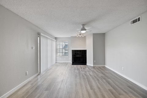 A spacious room with a fireplace and wood flooring.