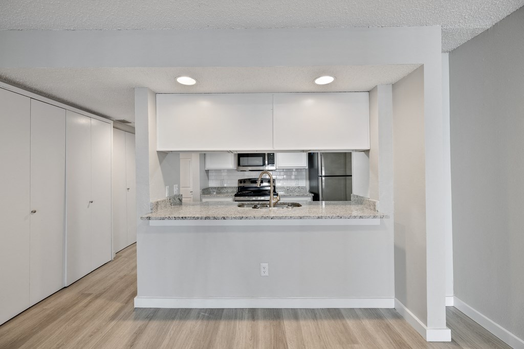 A kitchen with white cabinets and a marble countertop.
