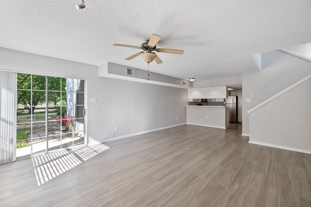 A spacious room with a ceiling fan and light wood flooring.