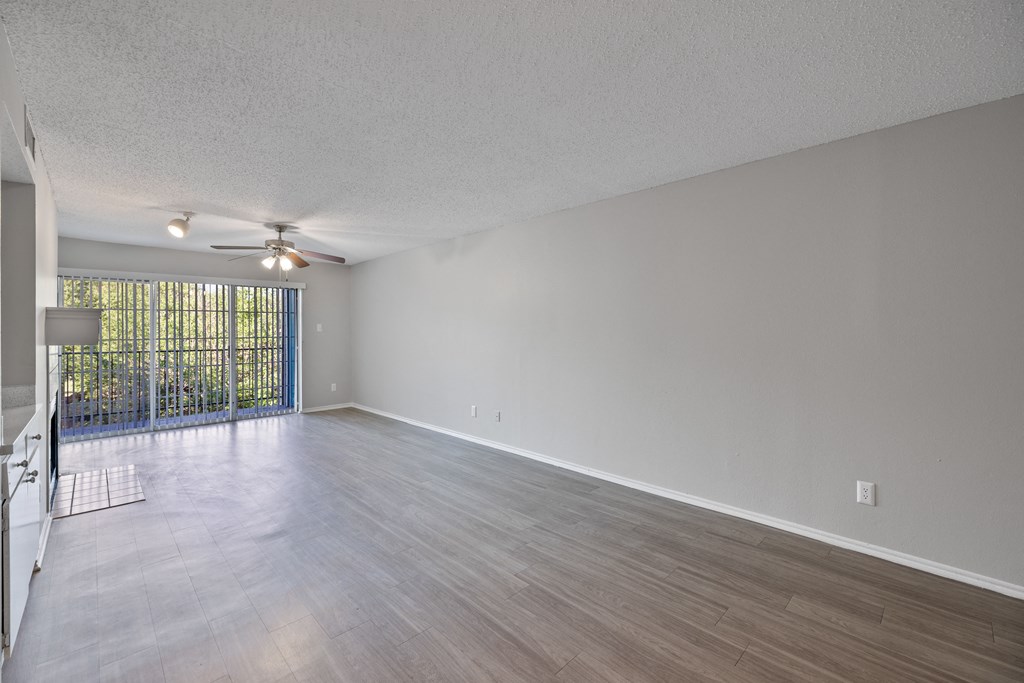 A room with a ceiling fan and sliding glass doors.