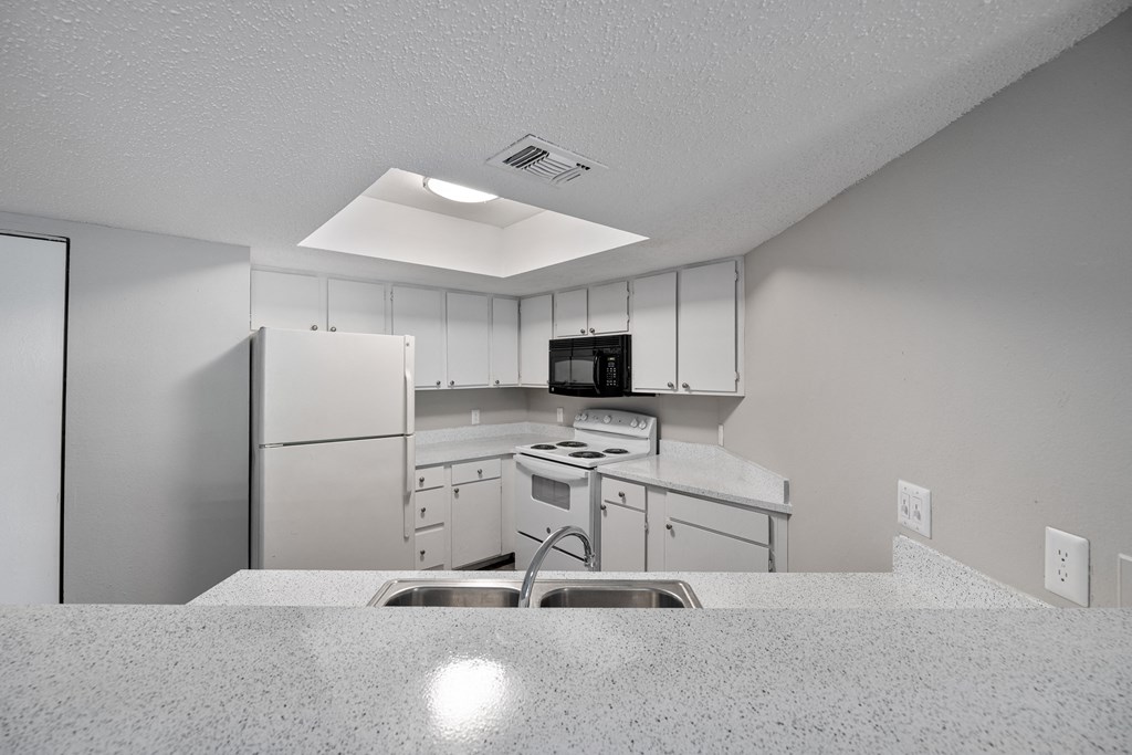 A kitchen with white cabinets and appliances.